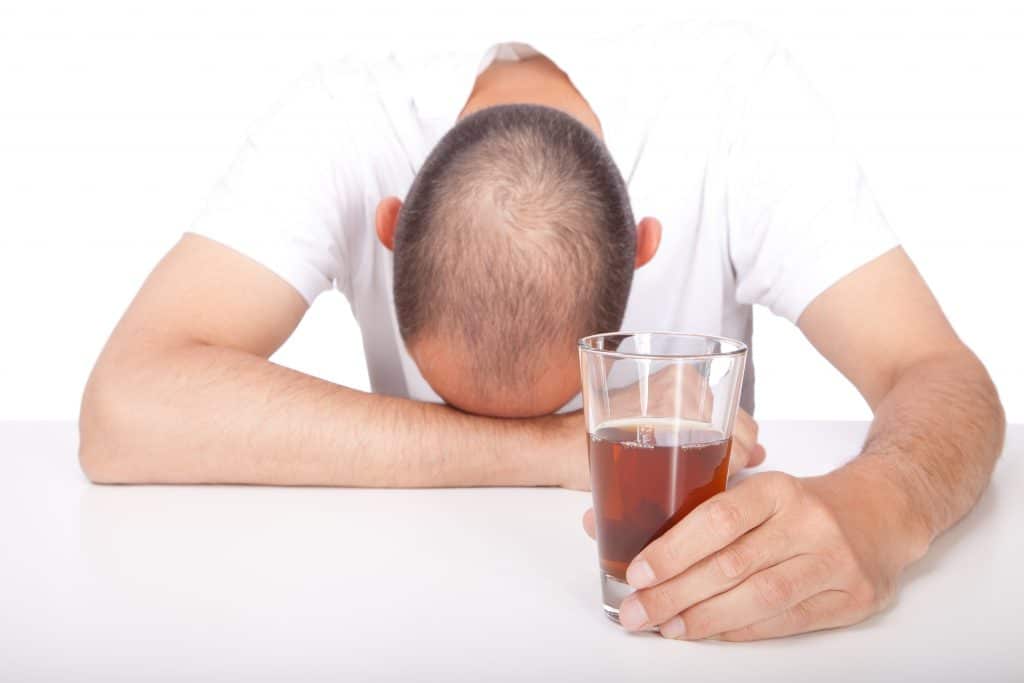 Man,With,His,Head,On,The,Table,Holding,An,Alcoholic