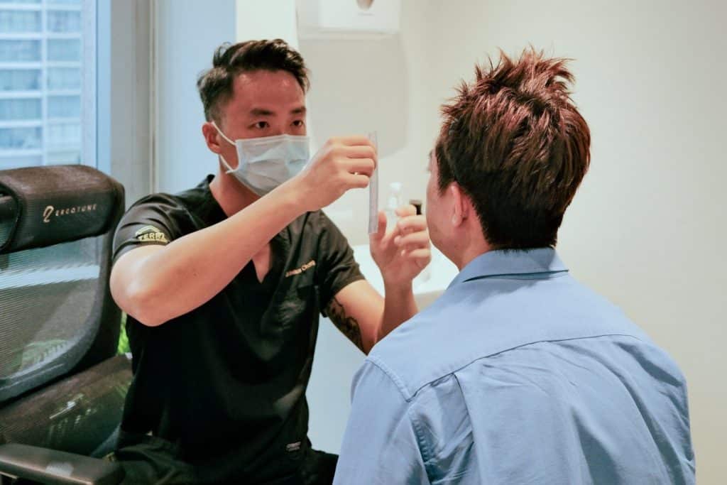 A Hair Restoration Doctor Drawing on a hair line on a patient during a consultation for a hair transplant